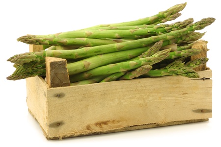  fresh green asparagus shoots in a wooden crate on a white backgroundの写真素材