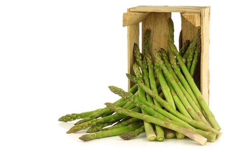 fresh green asparagus shoots in a wooden crate on a white backgroundの写真素材