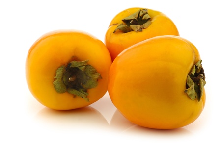 three fresh kaki fruits on a white backgroundの写真素材