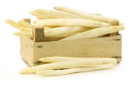 fresh white asparagus shoots,in a wooden crate on a white backgroundの写真素材
