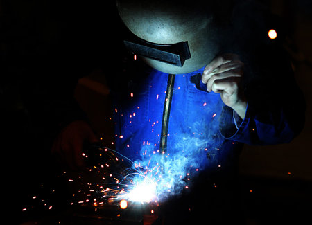 Welder at work with welding mask and torch