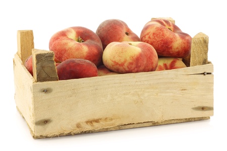  fresh colorful flat peaches  donut peaches  in a wooden crate on a white backgroundの写真素材