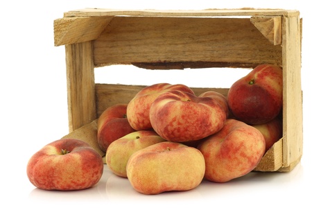  fresh colorful flat peaches  donut peaches  in a wooden crate on a white backgroundの写真素材