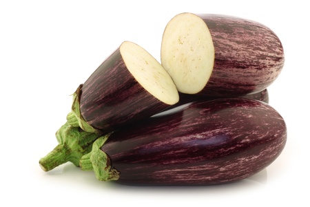 striped aubergines and a cut one on a white backgroundの写真素材
