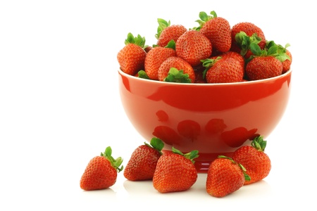 fresh strawberries in a red ceramic bowl on a white backgroundの写真素材