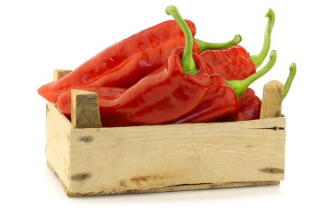 fresh red sweet peppers  capsicum  in a wooden crate on a white backgroundの写真素材