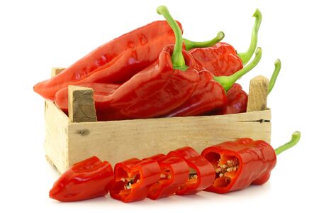 fresh red sweet peppers  capsicum  in a wooden crate on a white backgroundの写真素材