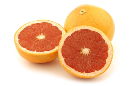 fresh red grapefruit and a cut one on a white backgroundの写真素材