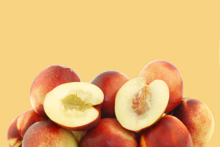 fresh nectarines and a cut one on a orange backgroundの写真素材