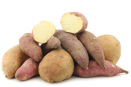 bunch of mixed sweet potatoes and a cut one on a white backgroundの写真素材