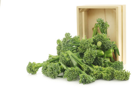 A small form of broccoli, called bimi, in a wooden box on a white backgroundの写真素材