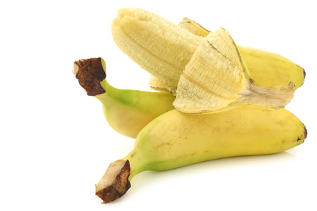 fresh mini bananas and a peeled one on a white backgroundの写真素材
