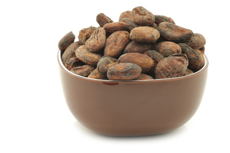 Dried cocoa beans in a brown bowl on a white backgroundの写真素材
