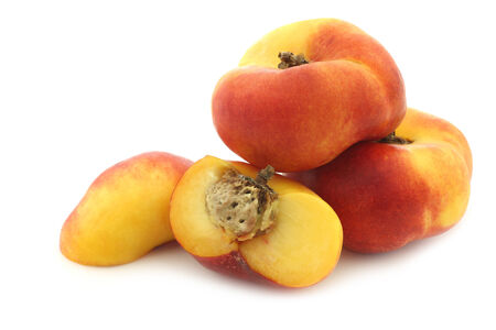 flat nectarines and a cut one on a white backgroundの写真素材