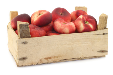 flat nectarines in a wooden crate on a white backgroundの写真素材