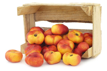 flat nectarines in a wooden crate on a white backgroundの写真素材
