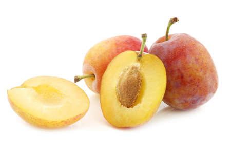 fresh ripe red and yellow plums and a cut one on a white backgroundの写真素材