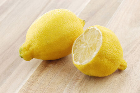 one whole and a dried out cut lemon on a wooden cutting boardの写真素材