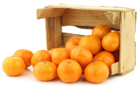 bunch of fresh tangerines in a wooden box on a white backgroundの写真素材