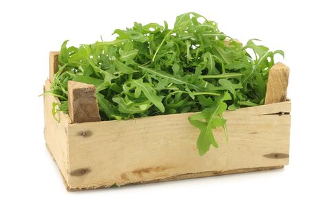 Eruca sativa fresh arugula leaves in a wooden box on a white backgroundの写真素材