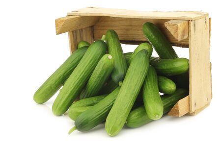fresh green snack cucumbers in a wooden box on a white backgroundの写真素材