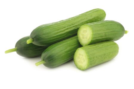 fresh green snack cucumbers and a cut one on a white backgroundの写真素材