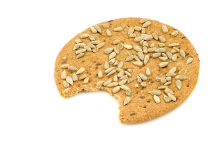 crispy spelled crackers with sunflower seeds with a bite missing on a white backgroundの写真素材
