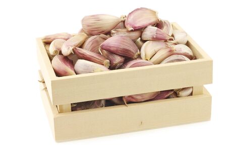 dried garlic cloves in a wooden box on a white backgroundの写真素材