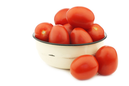 fresh and colorful italian roma tomatoes in an enamel bowl on a white backgroundの写真素材