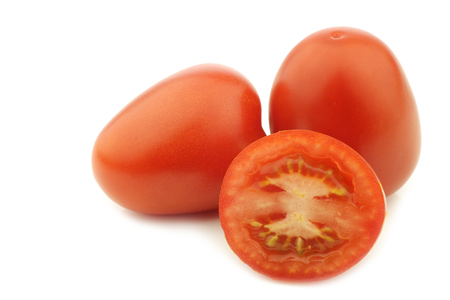 fresh and colorful italian roma tomatoes and a cut one on a white backgroundの写真素材
