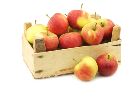 fresh red and yellow apples in a wooden crate on a white backgroundの写真素材