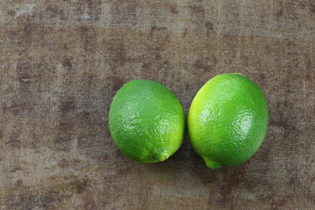 two lime fruits on a grungy metal background