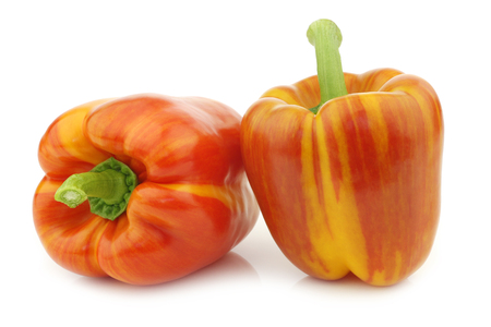 two fresh orange and red enjoya bell peppers (capsicum) on a white backgroundの写真素材