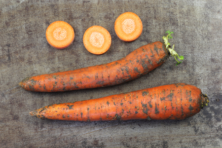 Winter carrots and some slices on a grungy metal backgroundの写真素材