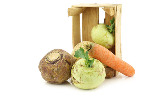 mixed cabbage and root vegetables in a wooden crate on a white backgroundの写真素材