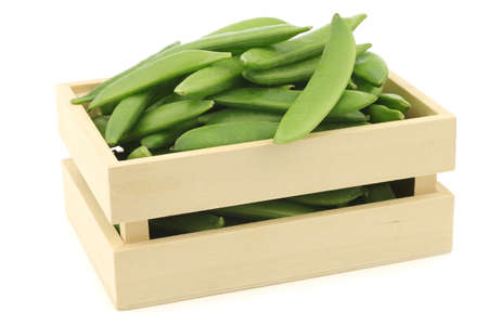 freshly harvested sugar snaps in a wooden box on a white backgroundの写真素材