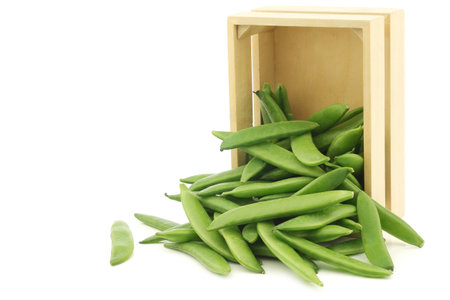 freshly harvested sugar snaps in a wooden box on a white backgroundの写真素材