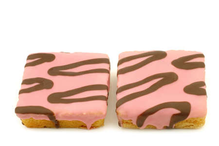 freshly baked square pink glazed cake with chocolate dressing on a white backgroundの写真素材