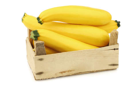 yellow zucchinis in a wooden crate on a white backgroundの写真素材