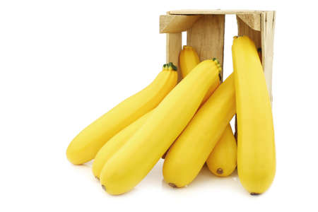 yellow zucchinis in a wooden crate on a white backgroundの写真素材