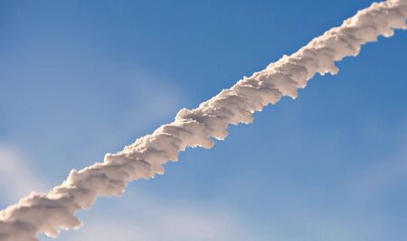 Frozen metal wire with blue sky in the backgroundの写真素材