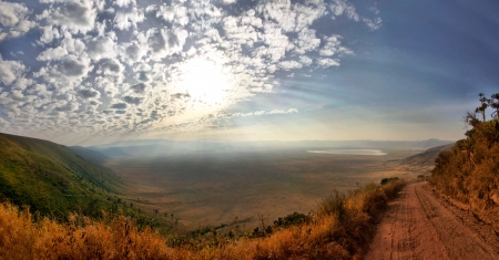 Panorama of Ngorongoro Crater with sunny blue sky with few clounds and gravel road.の写真素材