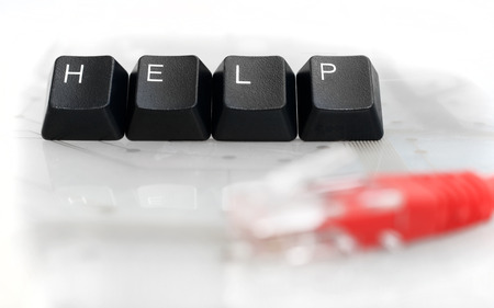 IT HELP - Four Black Keyboard Keys with Red Network Cable on White Glass Backgroundの写真素材