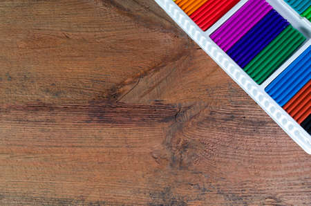 A set of multicolored crayons in a box on a wooden background.の写真素材