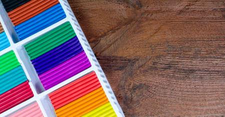 Colorful plasticine in a box on a wooden background with copy spaceの写真素材