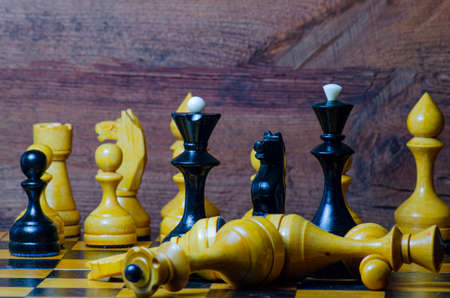 Chess pieces on a chessboard. Black and white figures on a wooden background.の写真素材