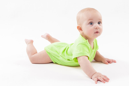 Surprised cute baby lying on his stomach and looking at the camera, picture with depth of fieldの写真素材