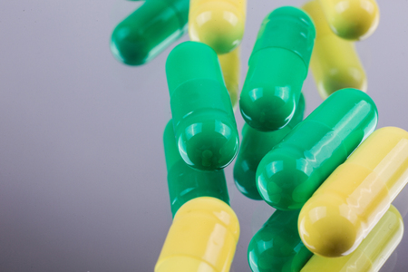 yellow and green on a mirrored medicine capsules background, macro, picture with depth of fieldの写真素材