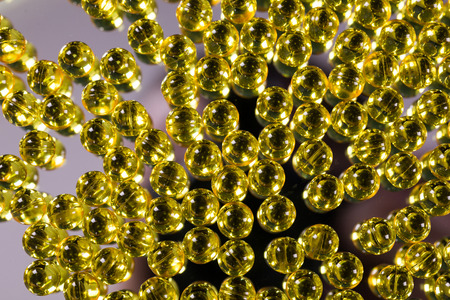 yellow medical capsules on a mirror surface picture with depth of field, macroの写真素材