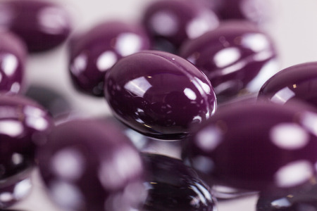 capsules purple pills on the mirror surface close up, macro, photos with depth of fieldの写真素材